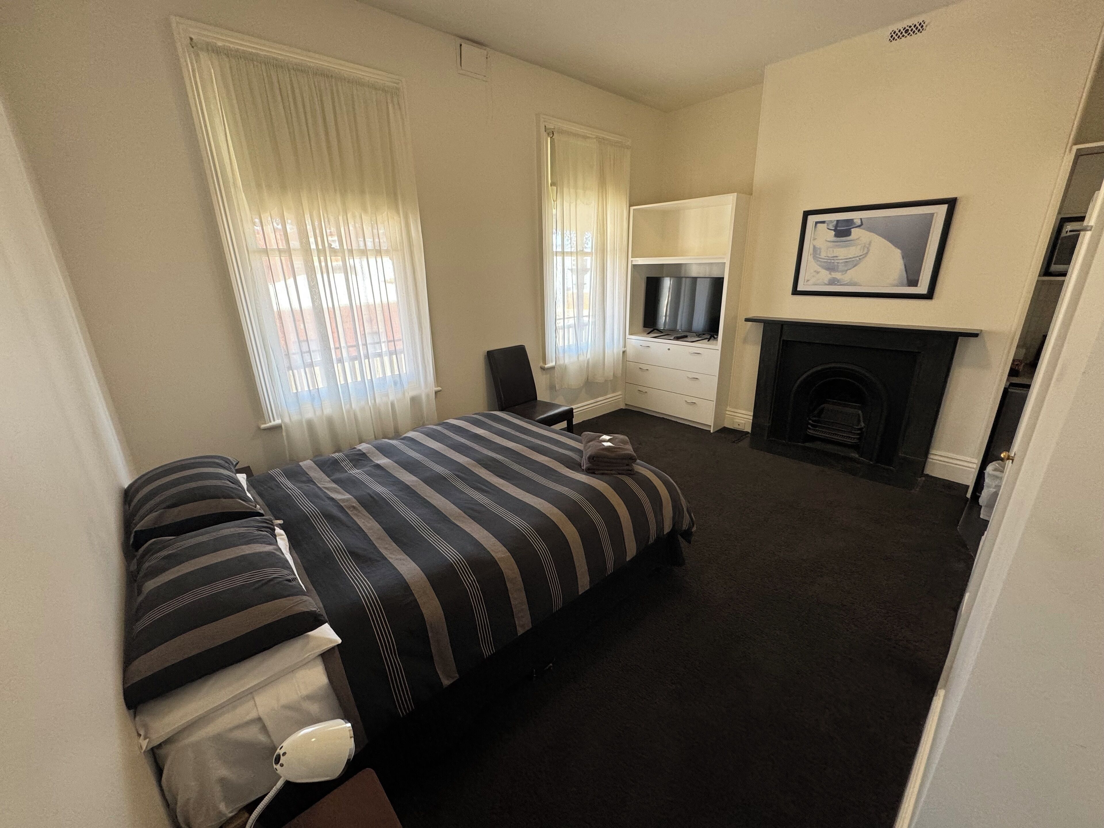 Habitación de hotel con cama, televisor, chimenea y ventana con cortinas.