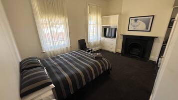 Habitación de hotel con cama, televisor, chimenea y ventana con cortinas.