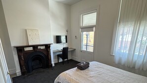 Ein Schlafzimmer mit einem großen Bett, einem Kamin, einem Schreibtisch und einem Fenster mit Vorhängen.