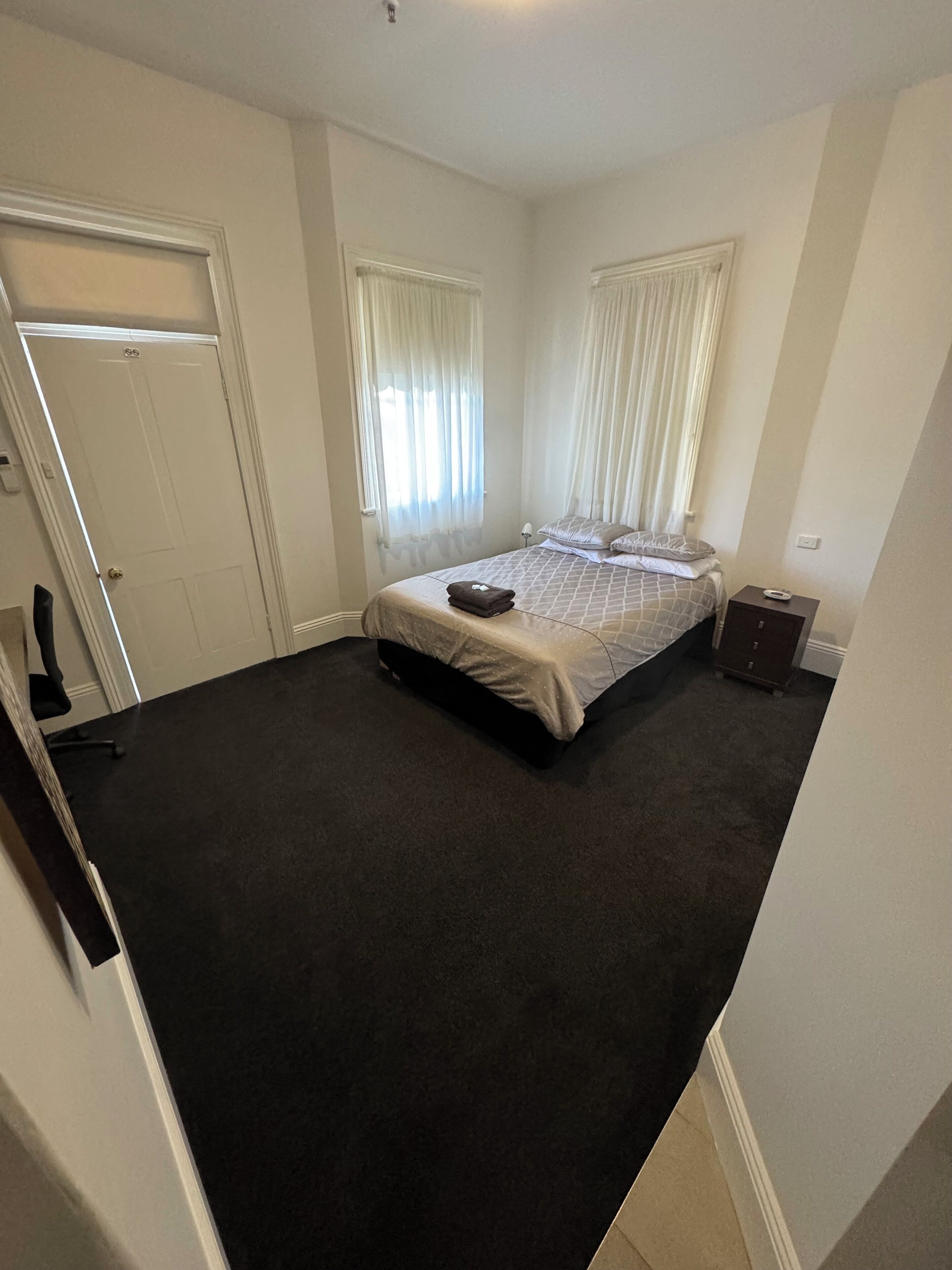 A bedroom with a bed, a nightstand, a desk, and a chair.