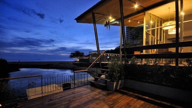A modern building with a wooden deck, a staircase, and a view of the water. - LG Lemon Grass (Sattahip)