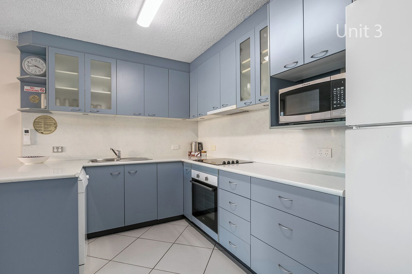 A kitchen with blue cabinets, a microwave, an oven, and a sink.
