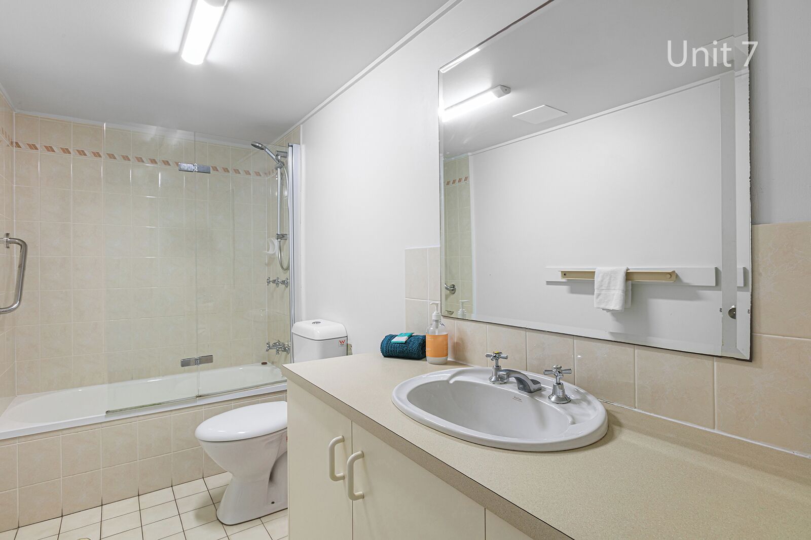 A modern bathroom with a bathtub, toilet, sink, and a large mirror.