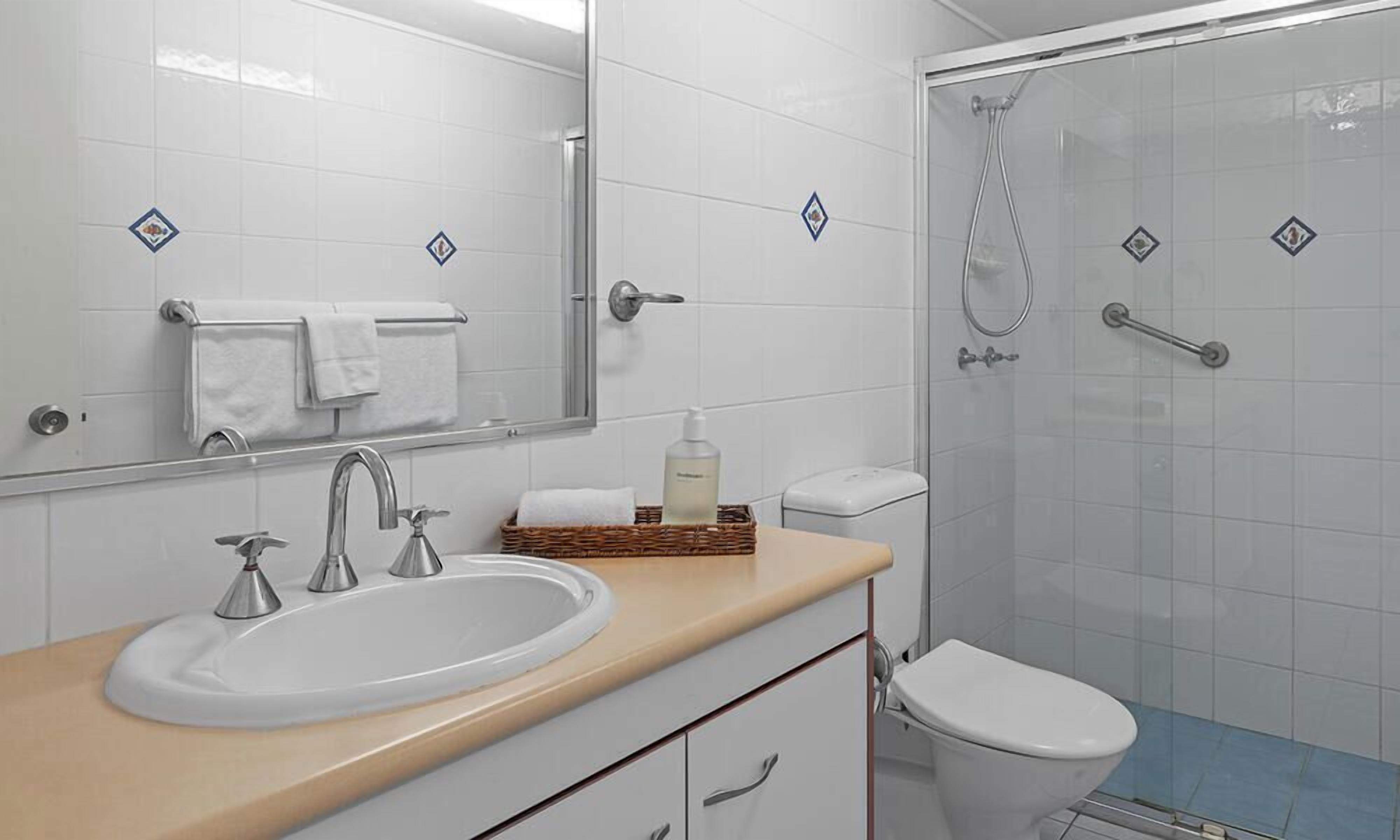 A modern bathroom with a sink, mirror, and toilet.