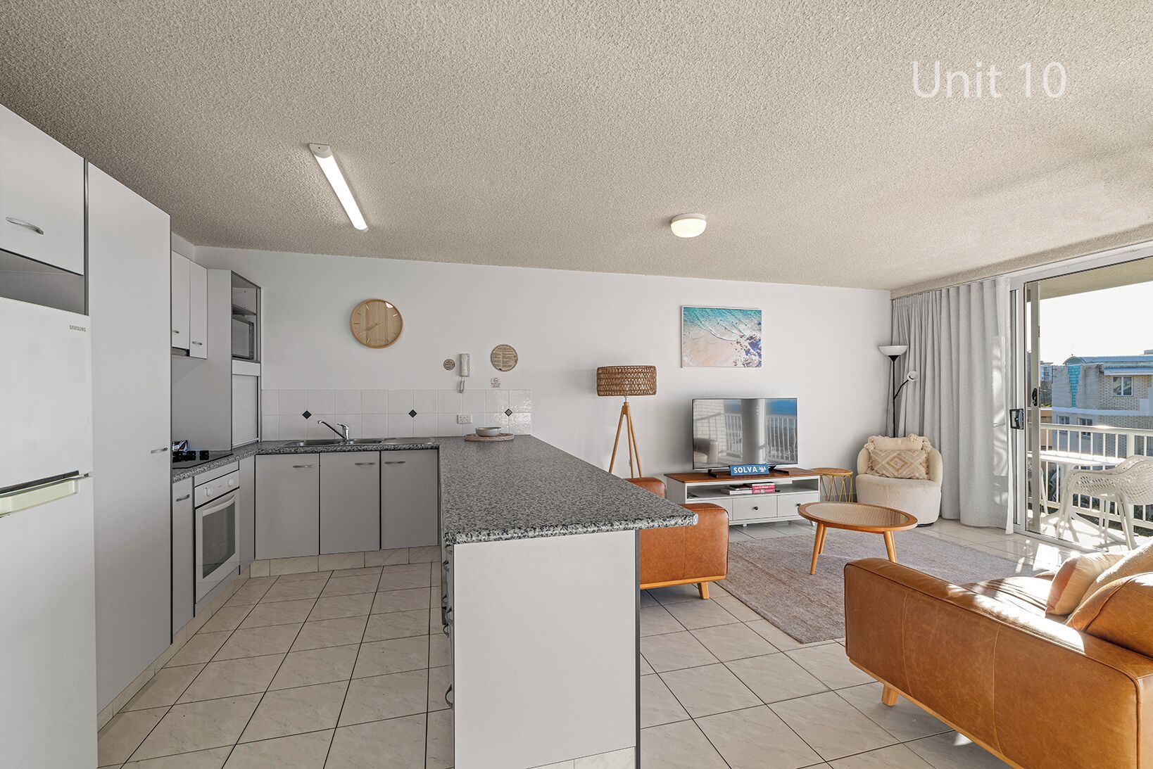 Un appartement moderne comprenant une cuisine, un coin repas et un salon. Il est équipé d’un téléviseur à écran plat, d’un canapé et d’un balcon avec vue.