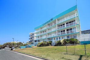 Experience the classic charm of Capeview, a hotel with a flat roof and balconies on each floor, set amidst a serene grassy area.