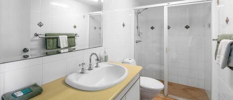 A modern bathroom with a sink, toilet, and walk-in shower.