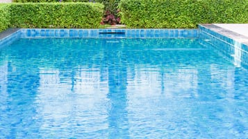 Una piscina al aire libre, sombrillas, tumbonas