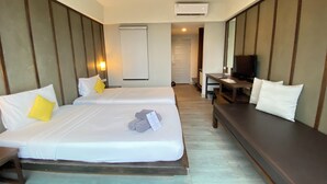 Una habitación de hotel con dos camas, un escritorio, un televisor y aire acondicionado.