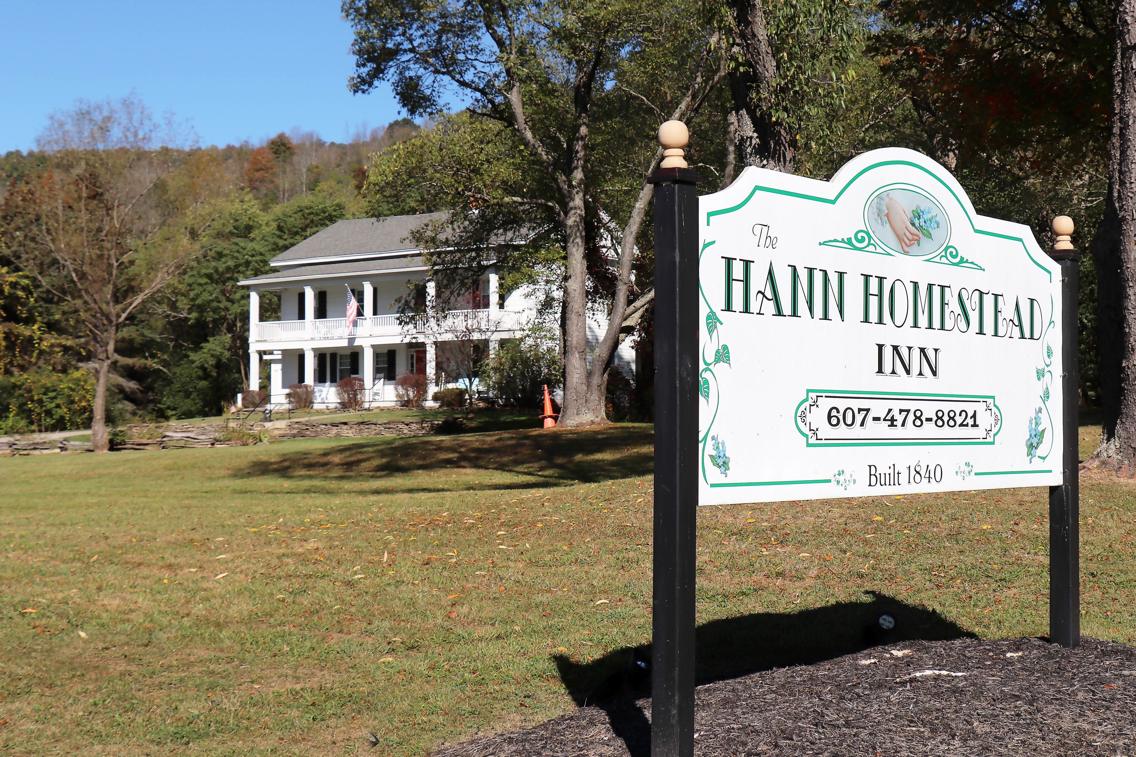 Señal del Hann Homestead Inn, con una casa de dos pisos al fondo.