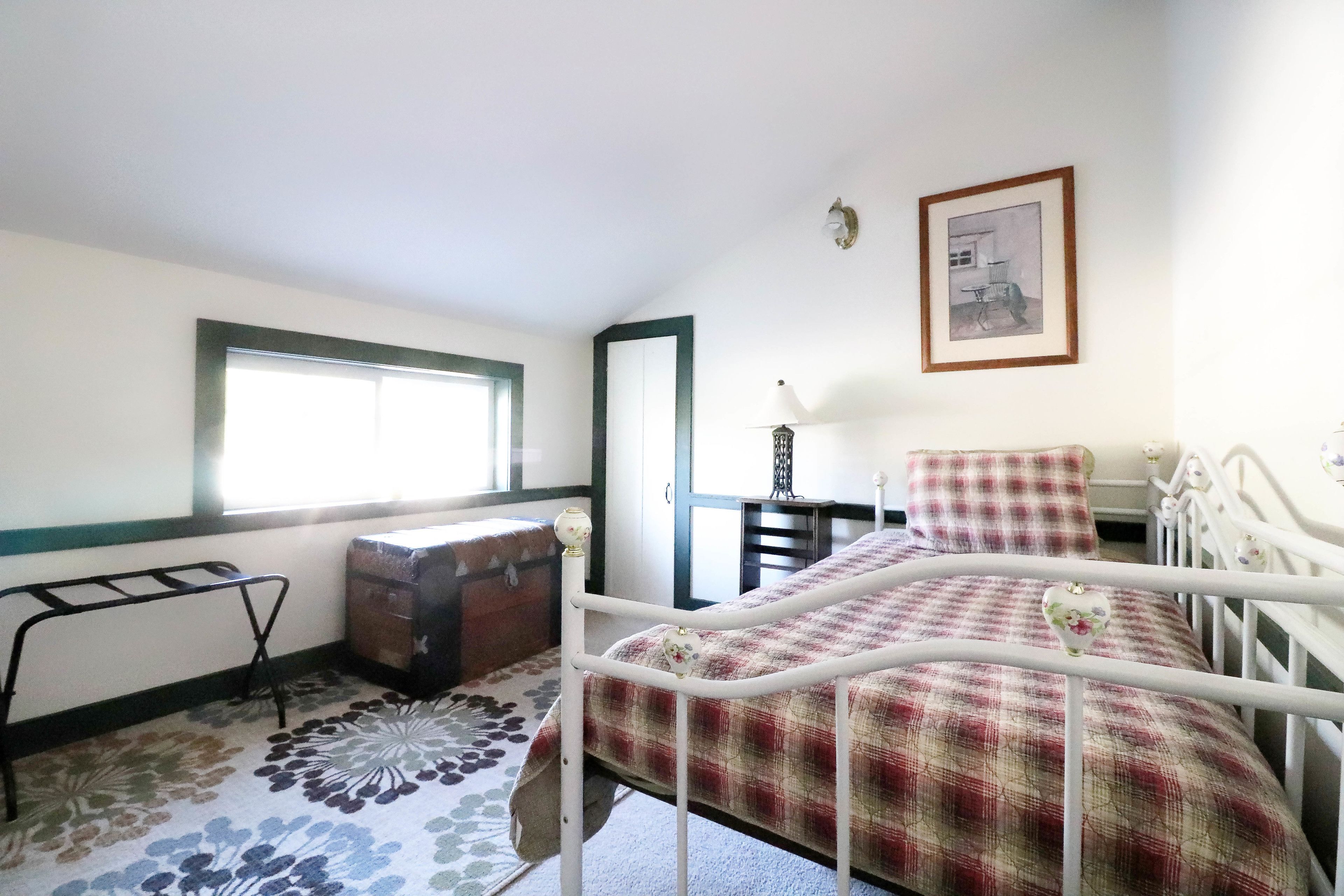 Une chambre à coucher avec un lit, une commode, une fenêtre et une porte.
