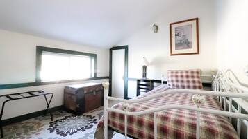 Une chambre à coucher avec un lit, une commode, une fenêtre et une porte.