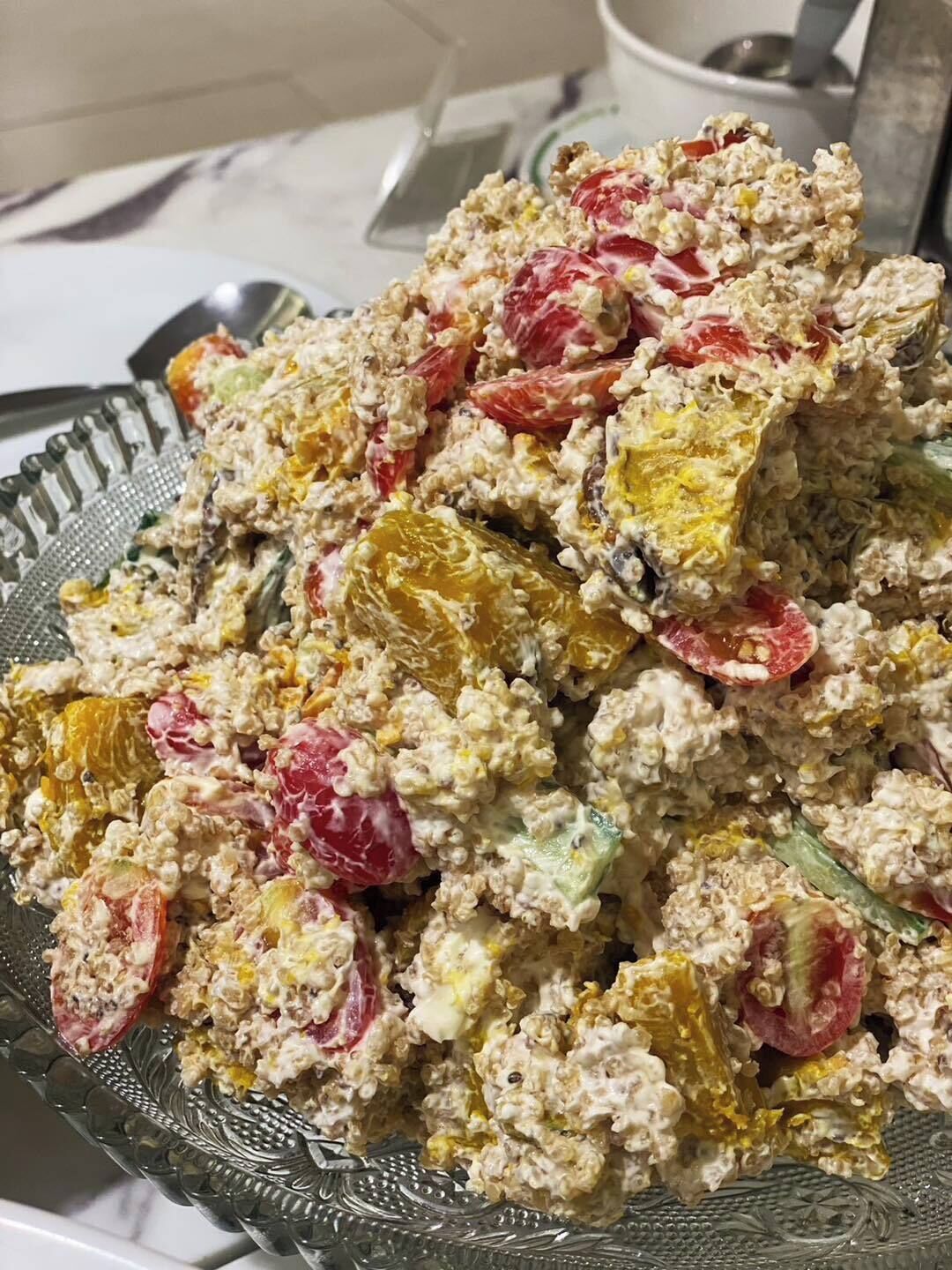 A glass bowl filled with a salad containing various fruits and vegetables.