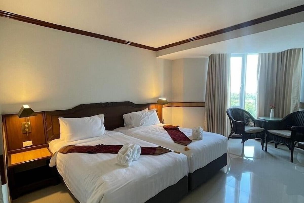 A hotel room with a large bed, bedside tables, a desk, and a chair.