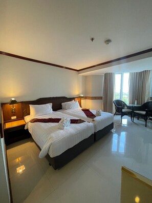 A hotel room with two beds, a desk, and a chair. - Suntara Wellness Resort & Hotel (Chachoengsao)