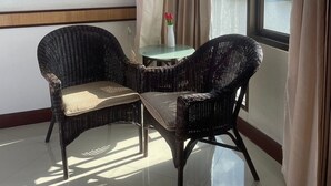 A corner room with two wicker chairs, a small table, and a view through a large window. - Suntara Wellness Resort & Hotel (Chachoengsao)