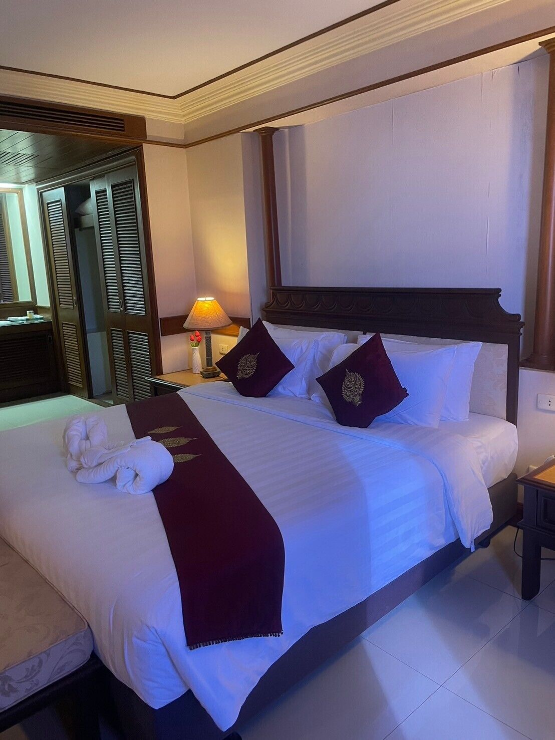Ein Hotelzimmer mit einem großen Bett, einem Nachttisch, einer Lampe und einem Kleiderschrank.