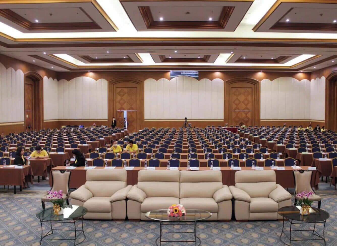 Une salle de conférence avec des rangées de chaises, un canapé central et un pupitre.