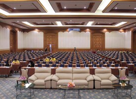 A conference room with rows of chairs, a central sofa, and a podium.
