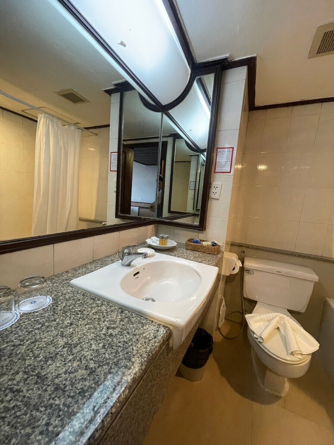 A bathroom with a granite countertop sink, a mirror, a toilet, and a shower curtain.