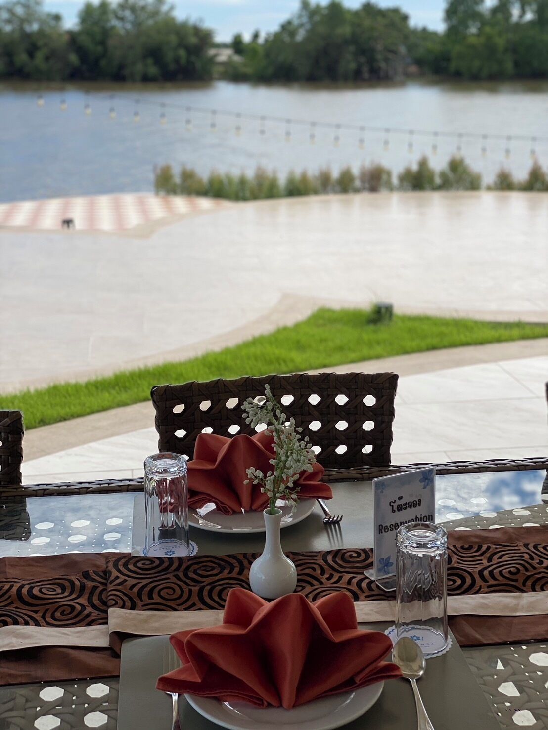 An outdoor dining table with a view of a lake, a sign indicating a reservation, and a decorative centerpiece.