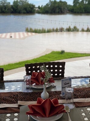 Una mesa de comedor al aire libre con vista a un lago, un letrero que indica una reserva y un centro de mesa decorativo.