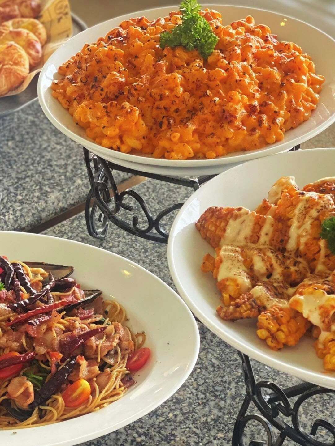 Three dishes on a table: pasta with a creamy sauce, a seafood dish with shrimp and vegetables, and a chicken dish with a creamy sauce.
