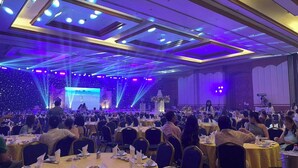 A banquet hall with round tables set for dining, a stage with a performer, and a large audience. - Suntara Wellness Resort & Hotel (Chachoengsao)