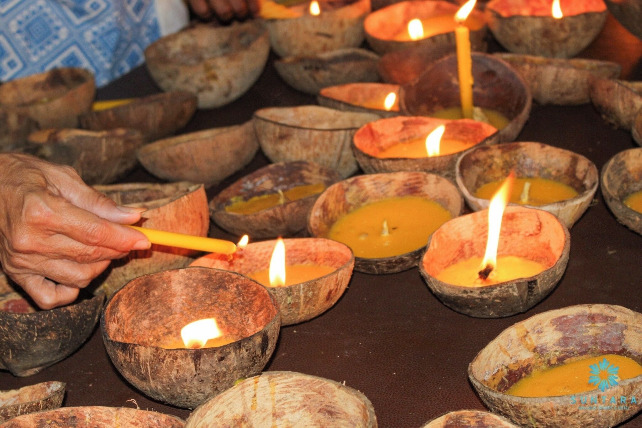 Una persona encendiendo velas en recipientes de cáscara de coco.