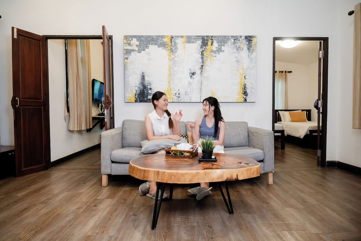Een moderne woonkamer met een grijze bank, een houten salontafel en een groot abstract schilderij aan de muur.