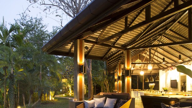 Un área lounge al aire libre moderna con piscina, asientos e iluminación ambiental.