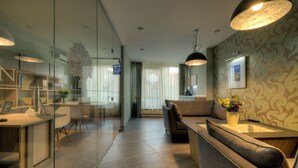 Un salon moderne doté d’une cloison en verre, d’un canapé, d’une table basse et d’un bureau avec un ordinateur.