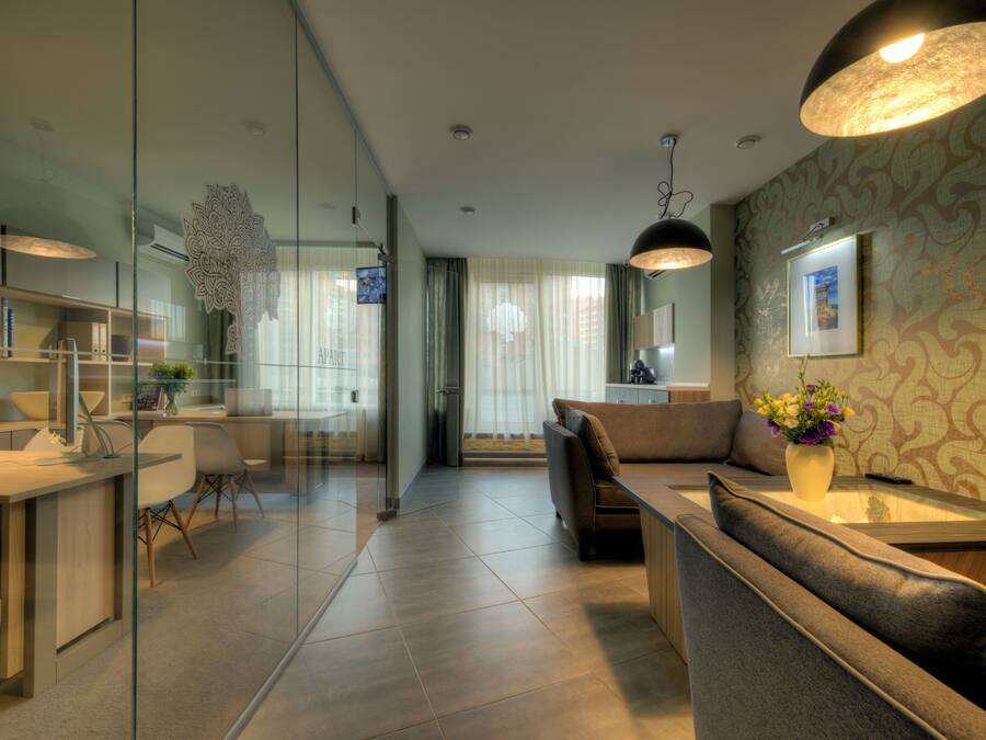 A modern living room with a glass partition, a sofa, a coffee table, and a desk with a computer.