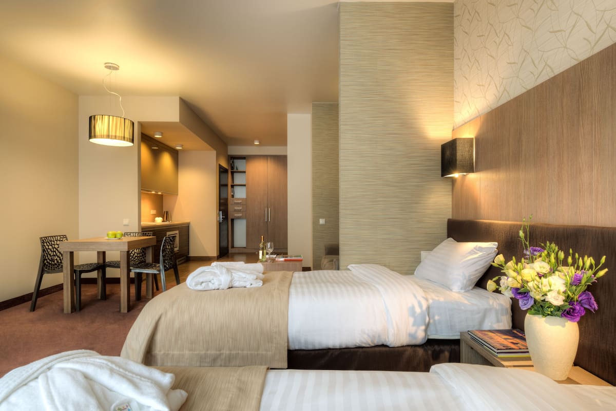 A hotel room with two beds, a desk, and a bathroom.