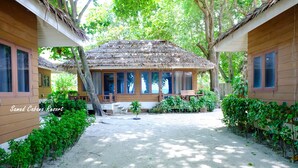 A resort with thatched-roof cabins, a sandy courtyard, and lush greenery. - Samed Cabana Resort (Rayong)
