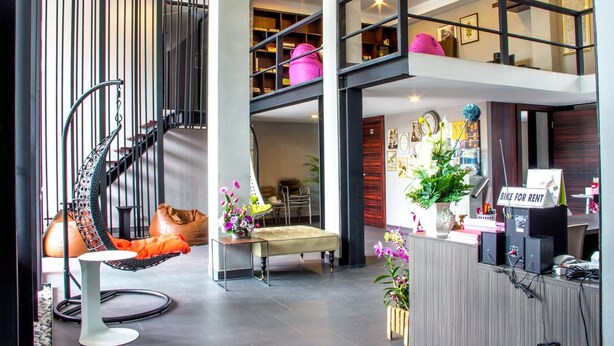 A modern interior with a spiral staircase, seating area, and a bike rental sign. - Siwa House (Pattaya)