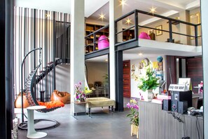 A modern interior with a spiral staircase, seating area, and a bike rental sign. - Siwa House (Pattaya)