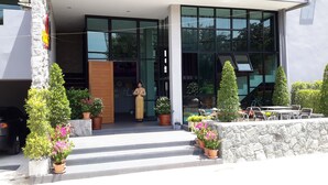 A modern building with a stone facade, large windows, and outdoor seating area with potted plants. - Siwa House (Pattaya)