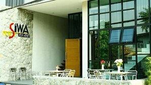 A modern building with a stone facade, large windows, and outdoor seating. - Siwa House (Pattaya)
