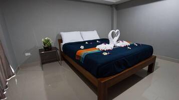 Uma cama bem arrumada com um cobre-leito azul, almofadas brancas e uma decoração de toalha em formato de coração.