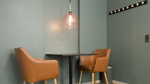 Un área de comedor moderna con dos sillones de cuero, una mesa redonda e iluminación colgante.