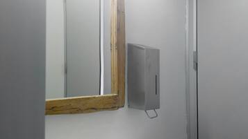 Un baño blanco con lavabo, espejo e iluminación.