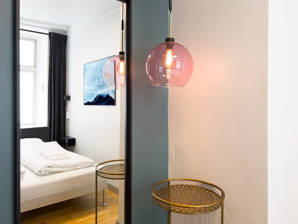 A hotel room with a bed, a round table, and a wall-mounted lamp.