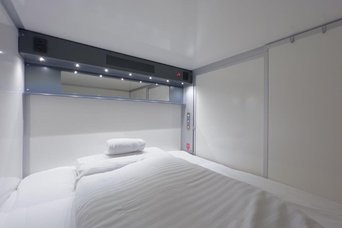 Ein Hotelzimmer mit einem Bett, einem großen Spiegel und einer Bedienkonsole.