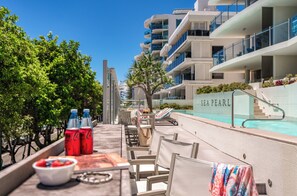 A poolside area with a table set for dining, chairs, and a view of the pool labeled "SEA PEARL".