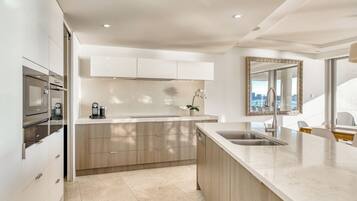 A modern kitchen with a central island, built-in oven, and a large mirror above the sink.