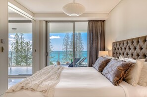 A bedroom with a large bed, a view of the sea, and a balcony.