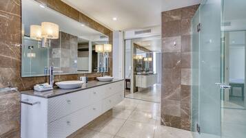 A modern bathroom with a large mirror, two sinks, and a glass shower enclosure.
