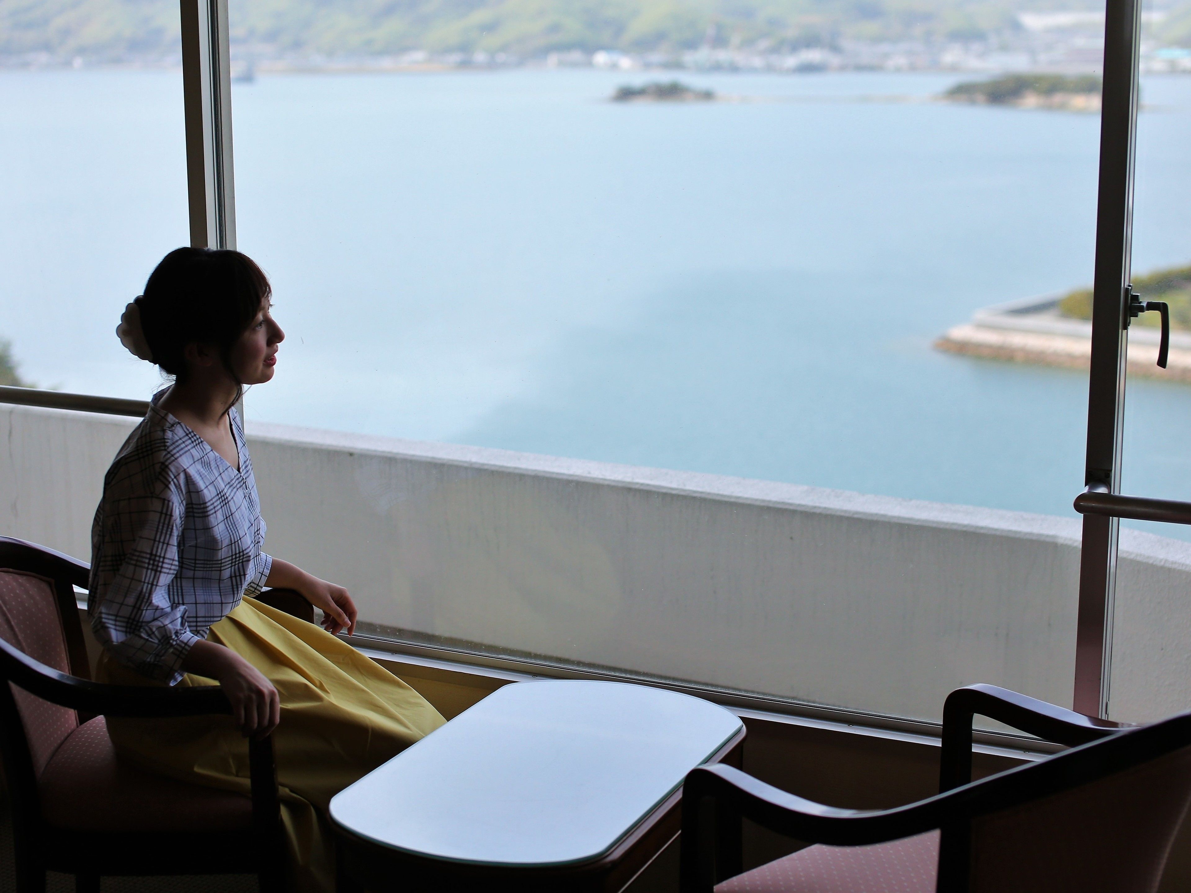 Una habitación con vista a un cuerpo de agua, una ventana y una mesa con sillas.
