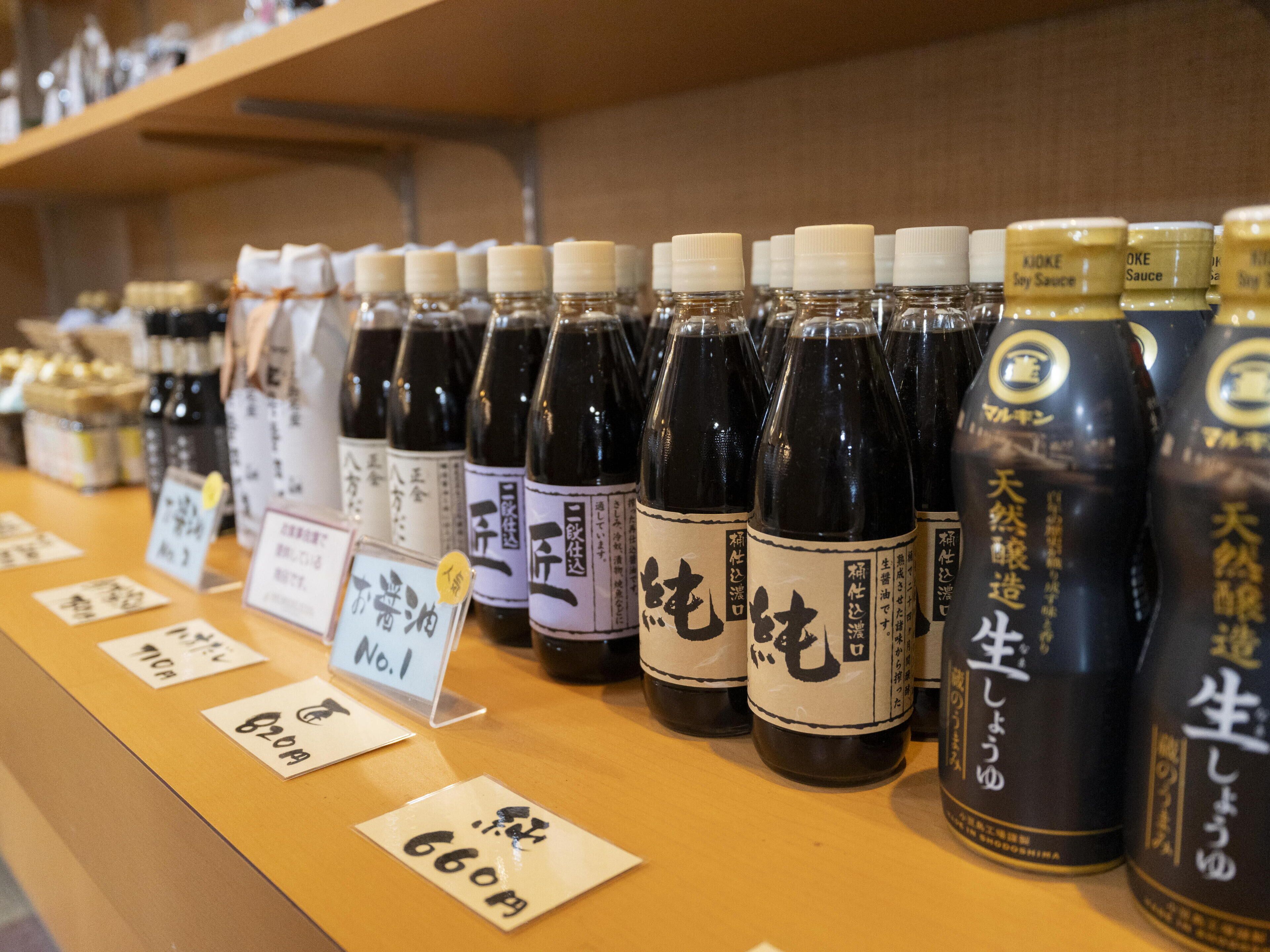 A display of soy sauce bottles with labels, arranged on a wooden shelf.